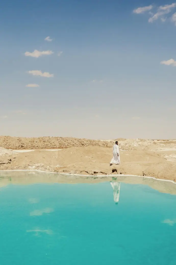 Crystal blue salt lake in Siwa Oasis reflecting desert sky
