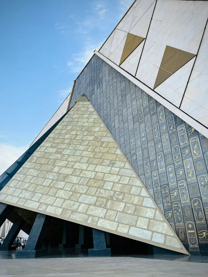 Exterior of the Grand Egyptian Museum in Giza, featuring modern architecture with ancient Egyptian design elements and hieroglyphic motifs.
