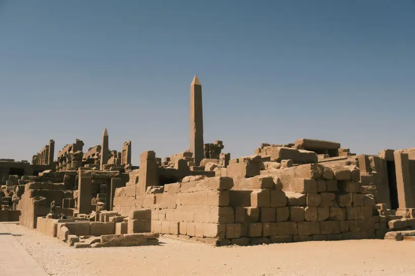 Ruins of Karnak Temple Complex in Luxor, Egypt with towering obelisks and ancient stone walls under clear blue sky — major archaeological site and historic religious center